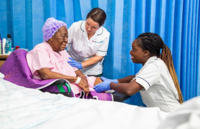 Two staff members with a patient by her bedside
