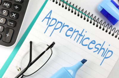 Notebook with the word 'apprenticeship' written on it, with calculator, glasses and marker all visible in the frame